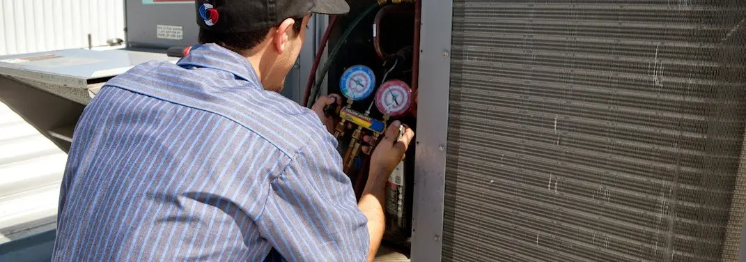 HVAC technician servicing a condenser unit in Kent